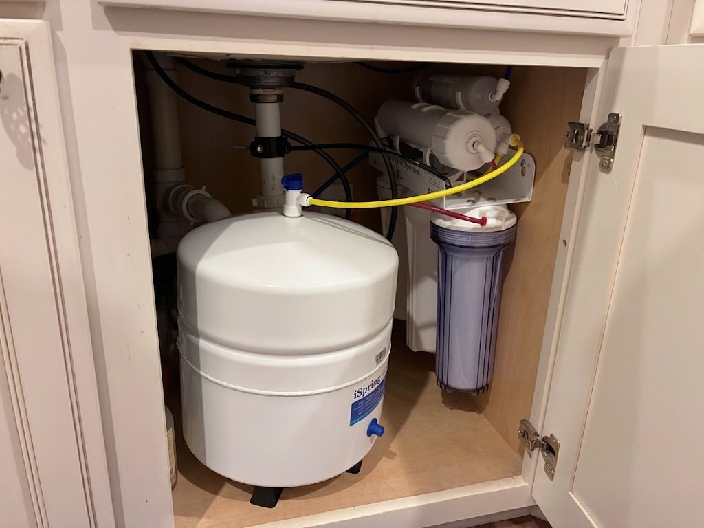 Reverse osmosis storage tank and filter housing installed inside a kitchen sink cabinet